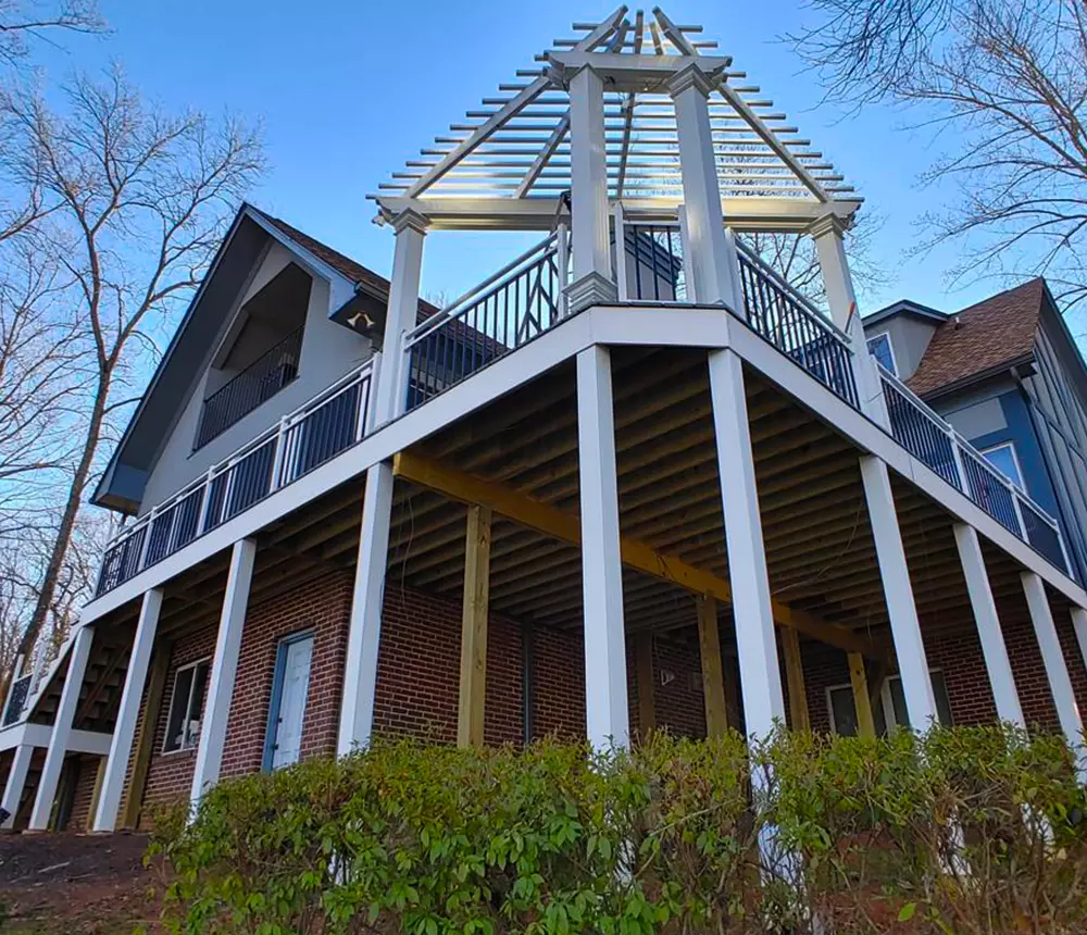 Two-story deck build in Tennessee with custom pergola, white column wrapped posts, and under-deck oasis
